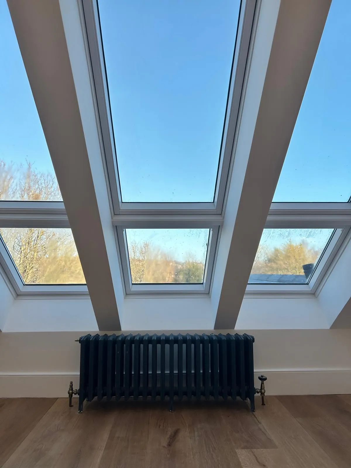 Attic conversion in Cork with three roof windows and a cast iron radiator beneath them